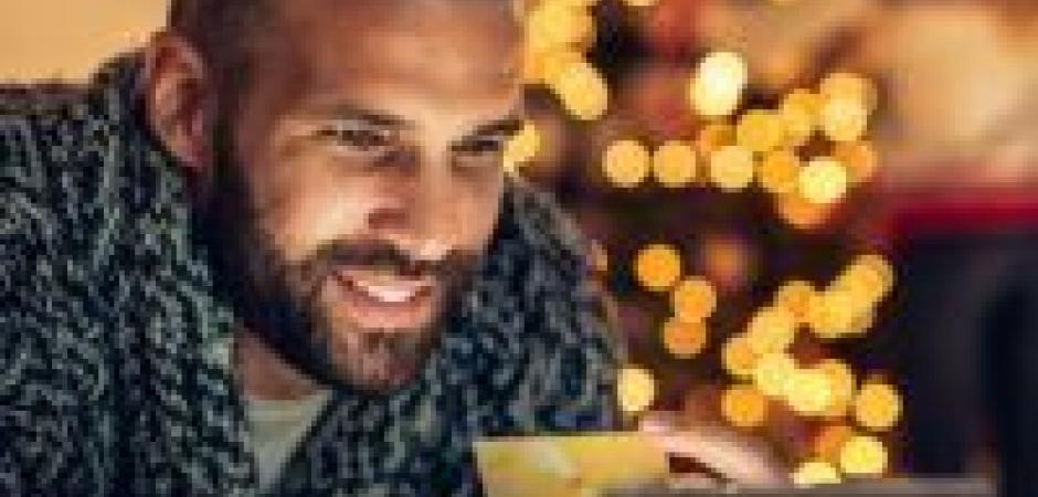 man on tablet by christmas tree